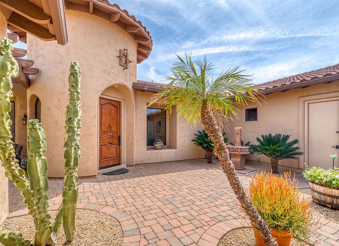 Personal Insurance - Exterior View of a Spanish Style Stucco Single Story Home with Pavers and Decorative Plants in Arizona
